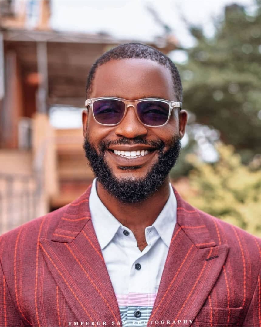 Portrait of Chukwuemeka (Peter) Muoneke, founder of Accelerator Community, smiling in a burgundy pinstripe blazer and tinted glasses